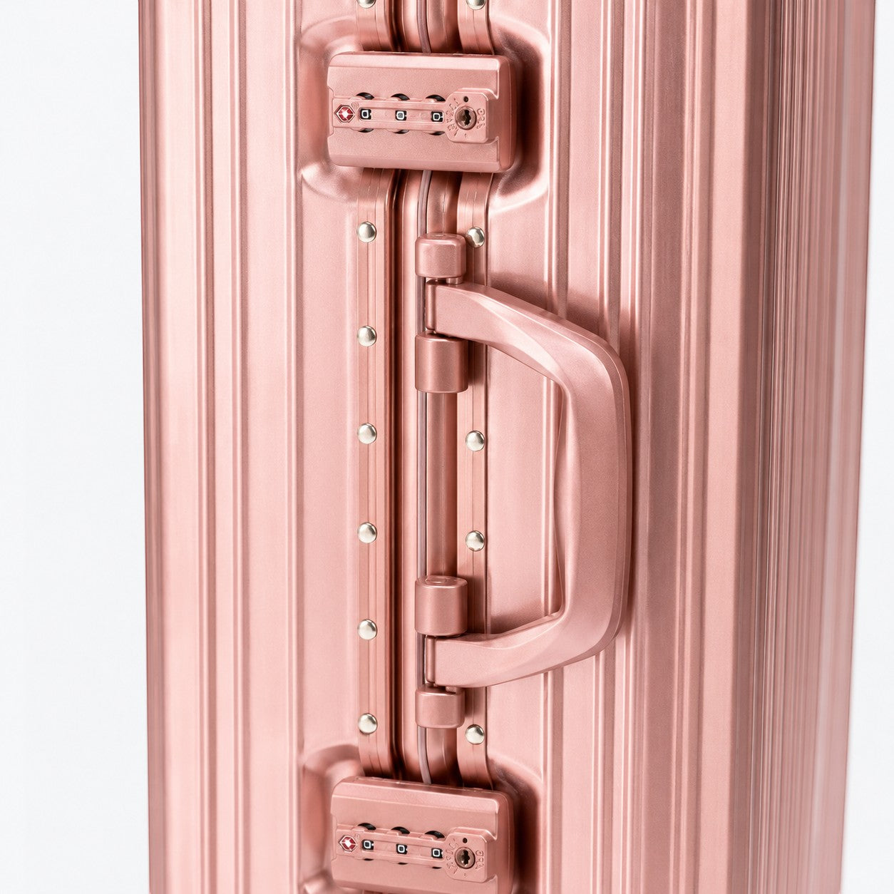 CASE.01 aluminum suitcase in rose gold with combination locks and a sturdy handle. Modern travel design.