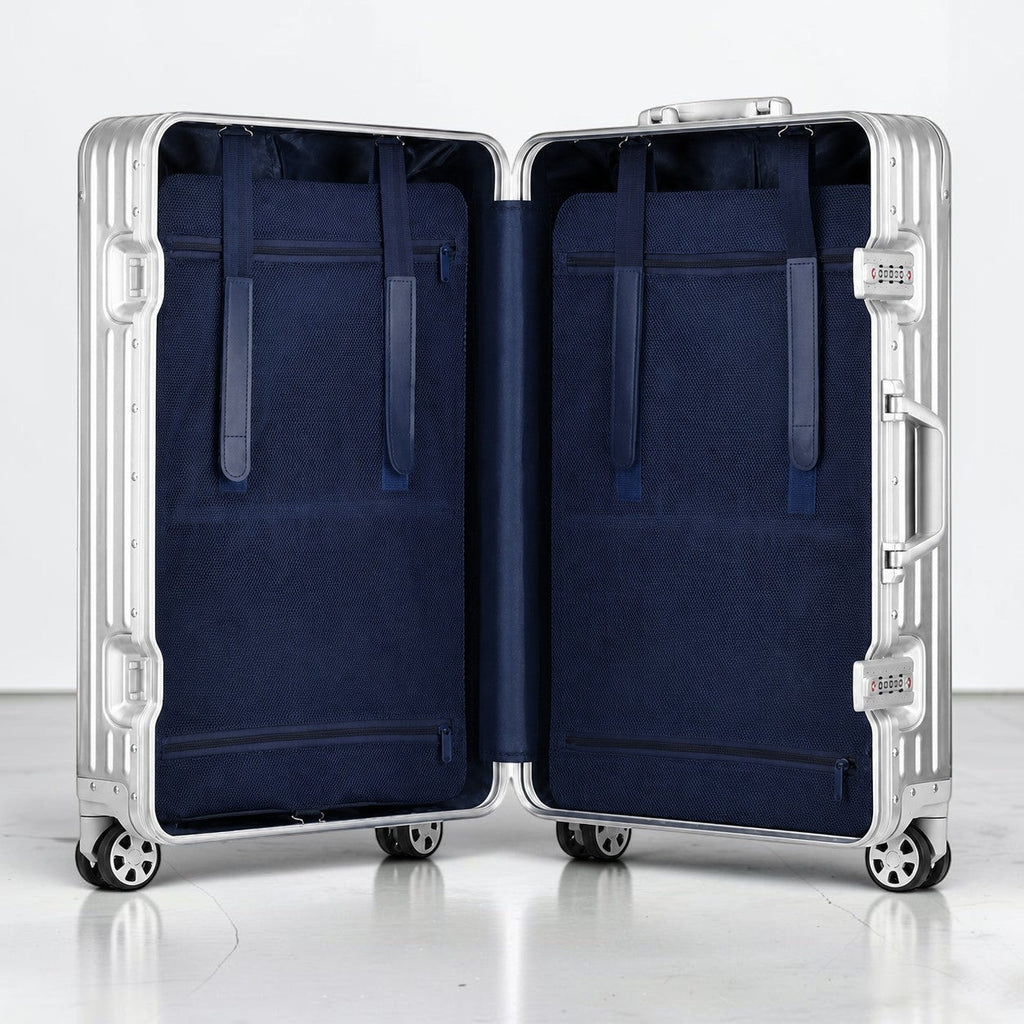 CASE.01 open aluminum suitcase with navy blue interior, straps, and zippered pockets. Silver.