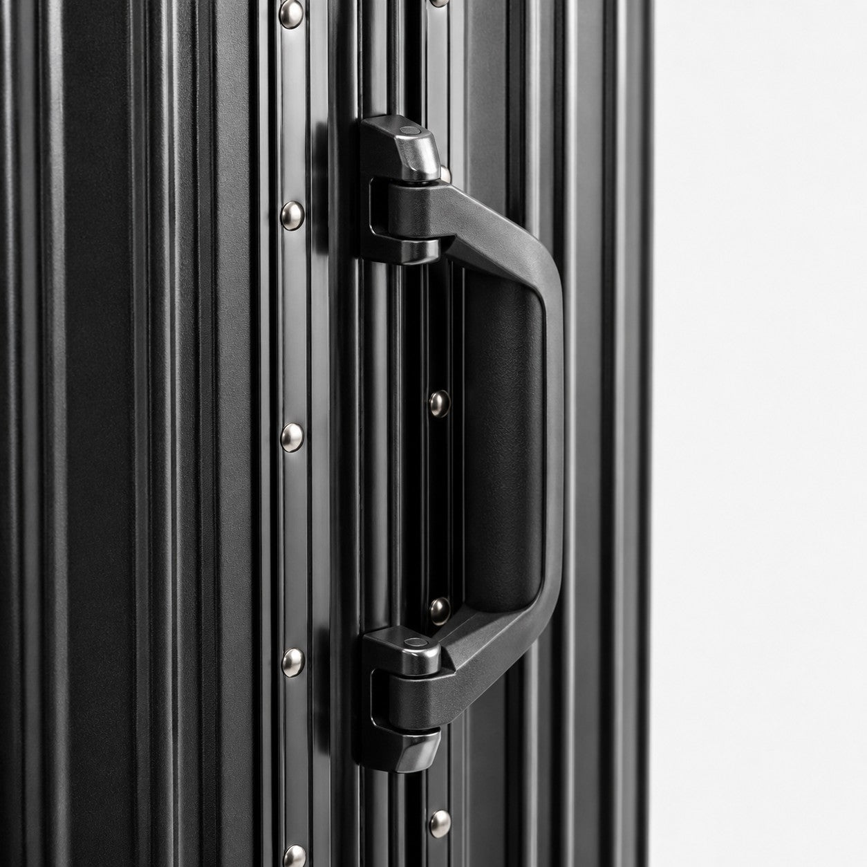CASE.01 aluminum suitcase in black with a sturdy handle and riveted details. Minimalist design for modern travel.